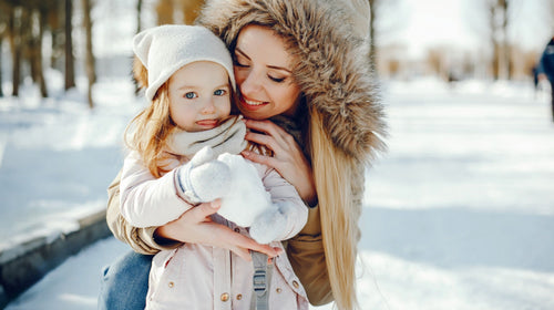 Mutter mit Tochter im Schnee – Symbolbild Grippe und Erkältung