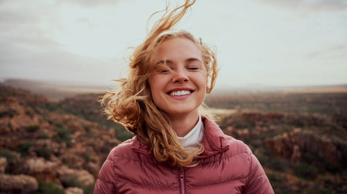 Frau entspannt in der Natur im Wind – Symbolbild Wohlfühl-Check