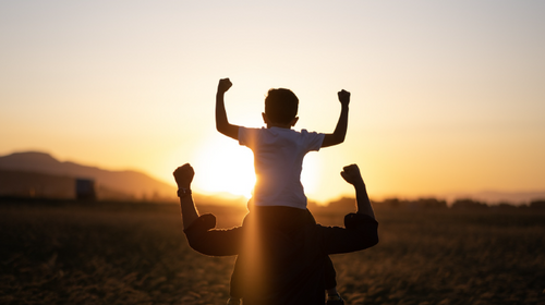 Kind auf den Schultern eines Erwachsenen bei Sonnenuntergang als Symbol für ein starkes Immunsystem